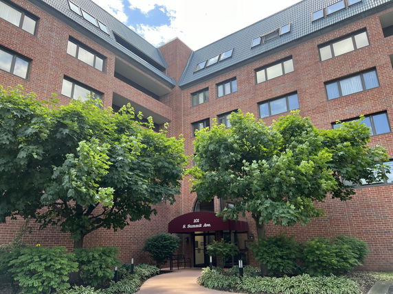 Front view of a multi-story brick building with large windows and a canopy at the entrance.