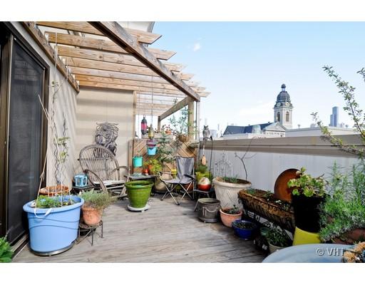 Rooftop with plants and seating area, featuring a pergola and cityscape view.