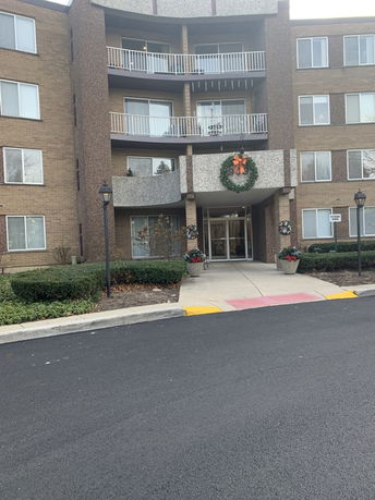 Front view of a multi-story brick building with balconies and holiday decorations.