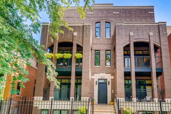 Front view of a modern multi-story brick building with balconies.
