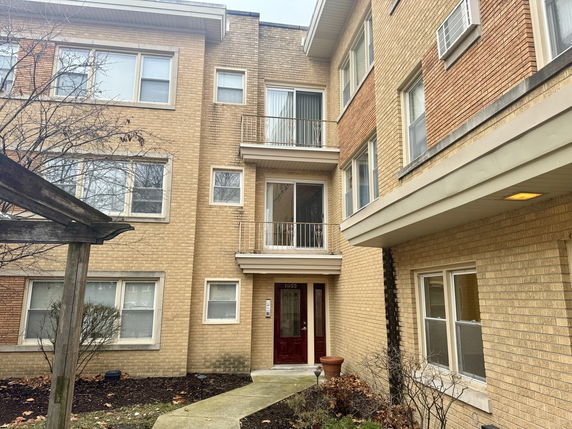 Front view of a multi-story brick apartment building with balconies.