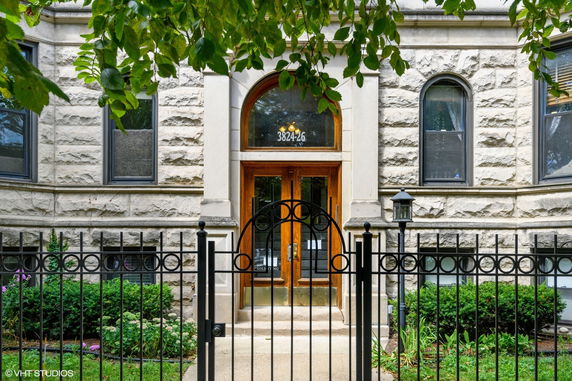 Front view of a stone building with arched windows and wooden doors.
