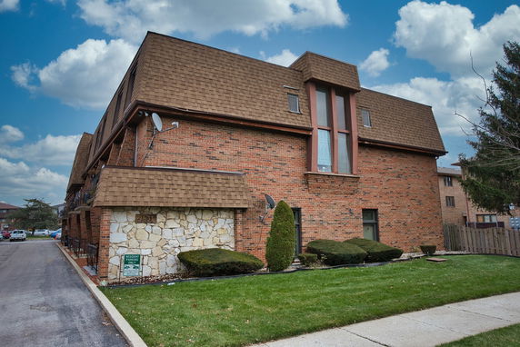 Front view of a two-story brick building with a brown roof and large windows.