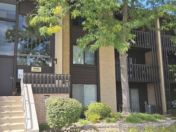 Front view of a multi-story building with balconies and large windows.