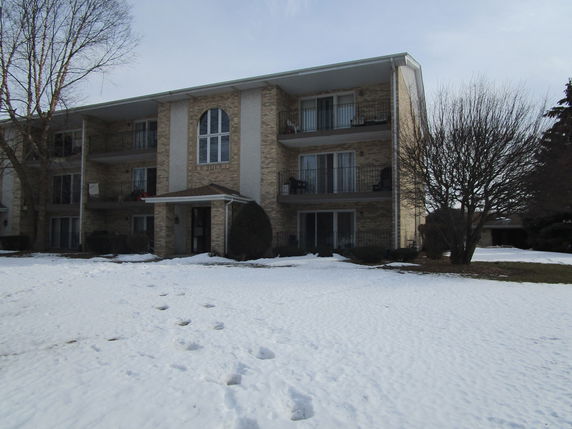 Front view of a three-story apartment building with balconies and an arched window.