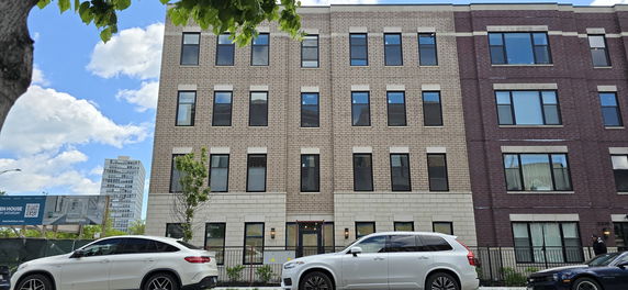 Front view of a three-story residential building with large windows.