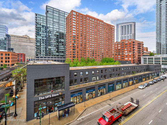 Front view of a commercial building with multiple stores and a modern glass high-rise in the background.