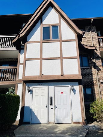 Front view of a multi-story building with Tudor-style design elements and two white doors.