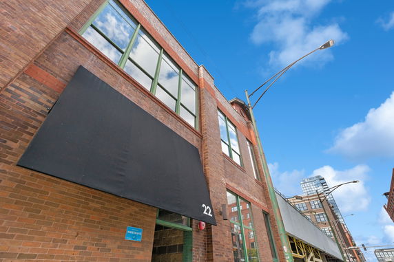Front view of a brick building with large windows and a black awning.
