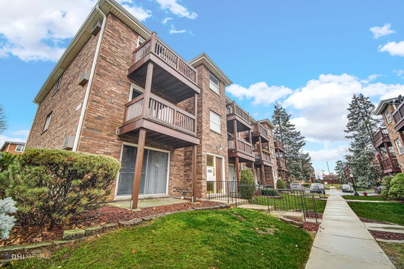 Front view of a multi-story brick apartment building with balconies.
