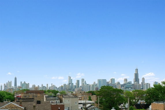 Panoramic view of a city skyline with various skyscrapers under a clear blue sky.