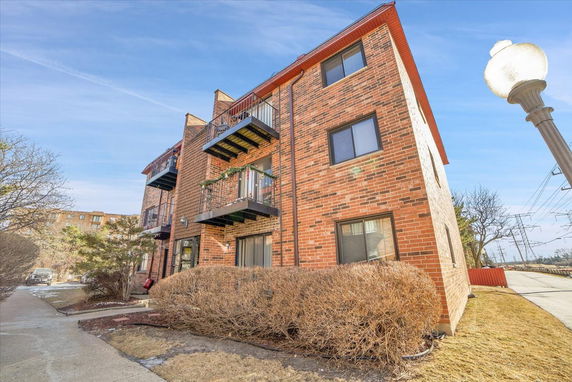 Front view of a three-story brick apartment building with balconies.