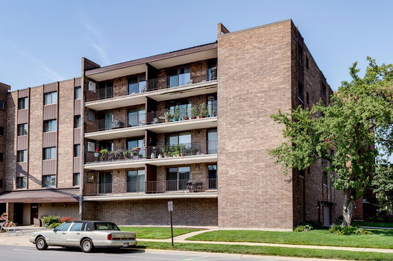 Front view of a multi-story brick apartment building with balconies.