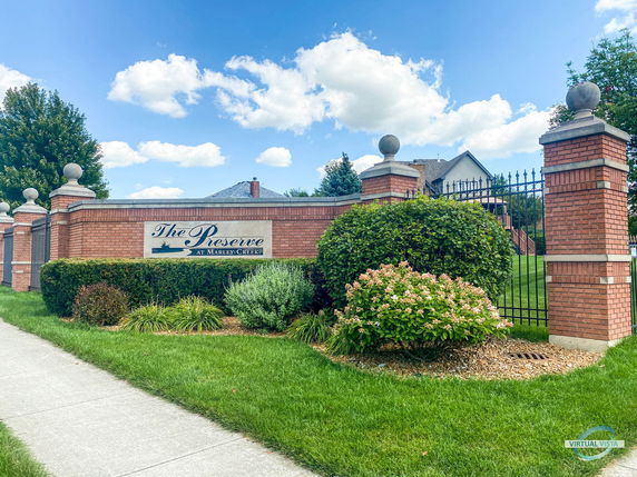 Front view of a landscaped entrance with a brick wall and metal gate.