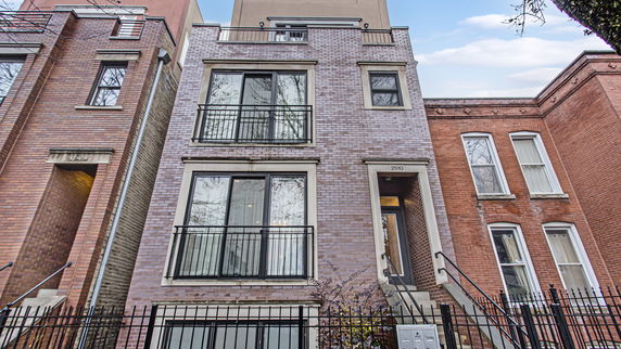 Front view of a multi-story brick townhouse with large windows and balconies.