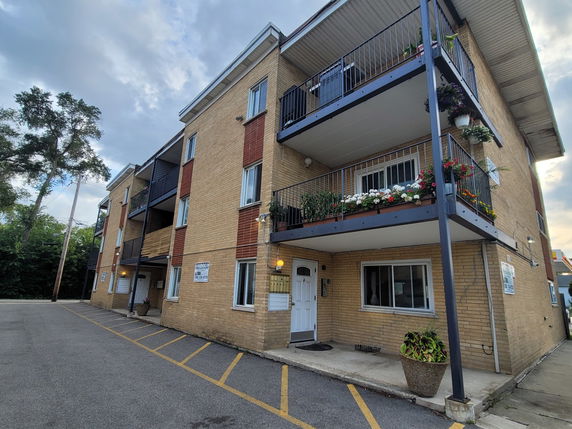Front view of a three-story apartment building with brick exterior and balconies.
