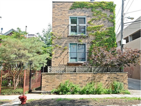Front view of a two-story brick house with climbing plants on the facade.
