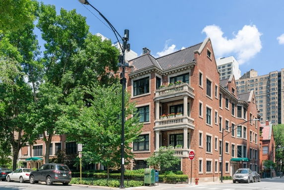 Front view of a multi-story brick building with balconies and gabled roof.