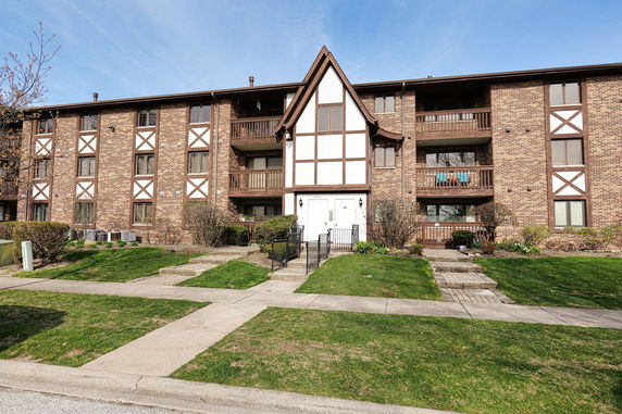 Front view of a multi-story brick building with balconies and a central entrance.