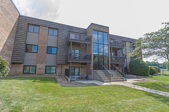 Front view of a three-story apartment building with brick and shingle exterior and balconies.