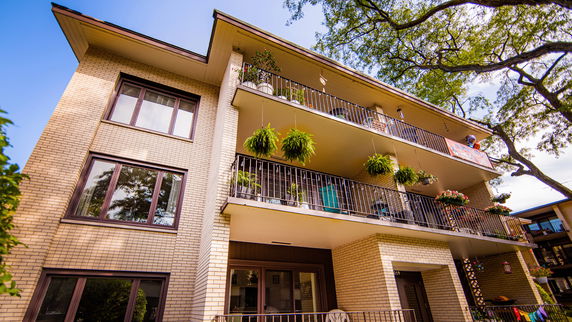Front view of a multi-story residential building with balconies and brick exterior.