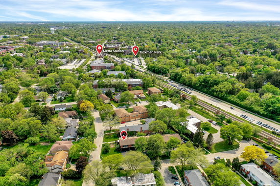 Panoramic view of a suburban area with roads, trees, and buildings in the foreground and distance.