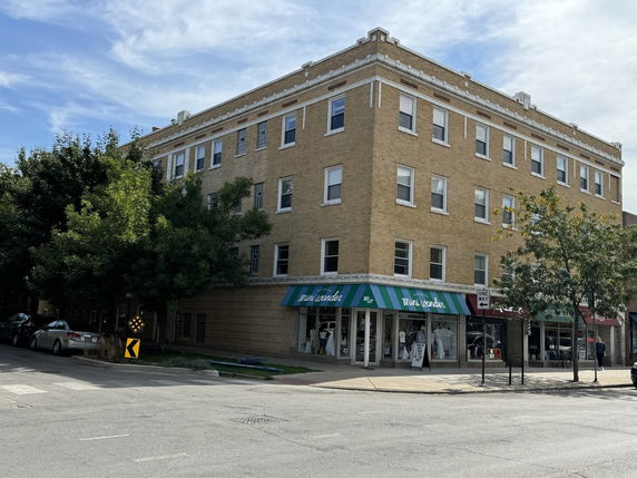 Front view of a multi-story brick building with retail stores on the ground floor.