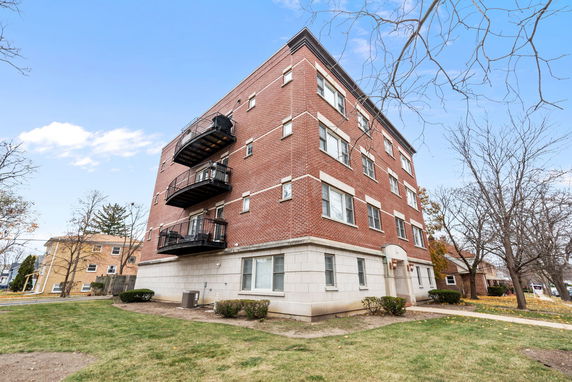 Front view of a multi-story brick apartment building with balconies.