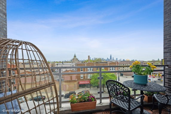 View from a balcony showcasing a cityscape, metal railing, and outdoor seating.