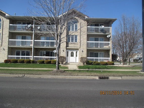 Front view of a multi-story apartment building with balconies.