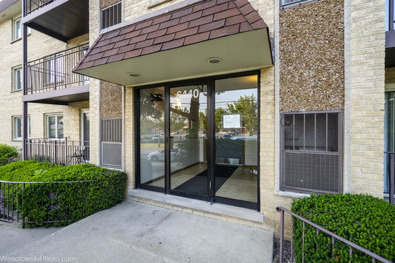 Front view of a building entrance with glass doors and balconies.