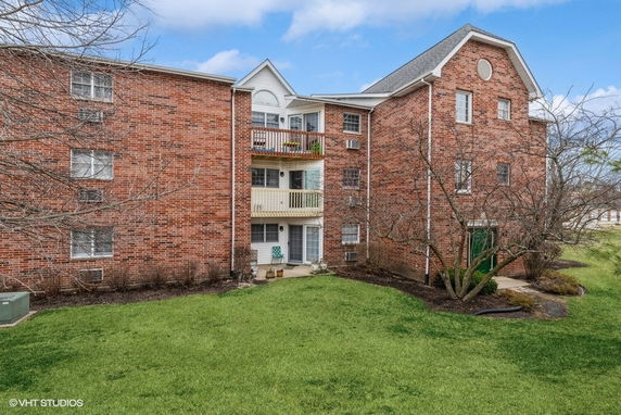 Front view of a three-story brick apartment building with balconies.