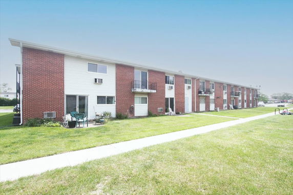 Front view of a row of two-story brick and siding apartment buildings.
