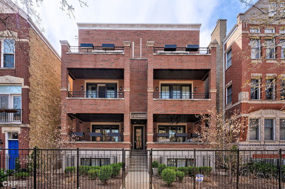 Front view of a brick multi-story residential building with balconies.