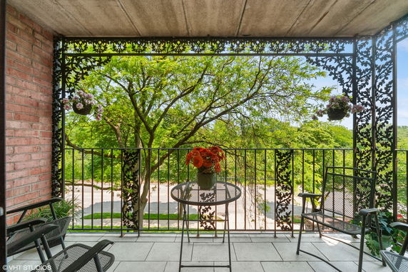 Balcony view with metal railings and lush green trees.