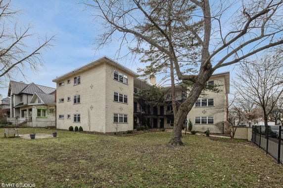 View of a multi-story brick apartment building with a spacious front yard.
