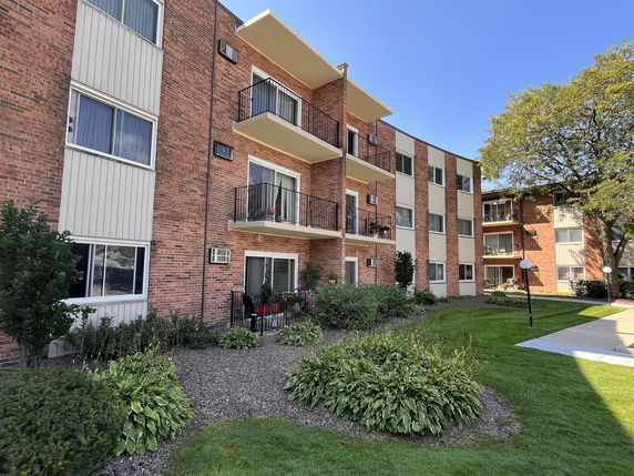 Front view of a multi-story residential building with balconies and brick exterior.