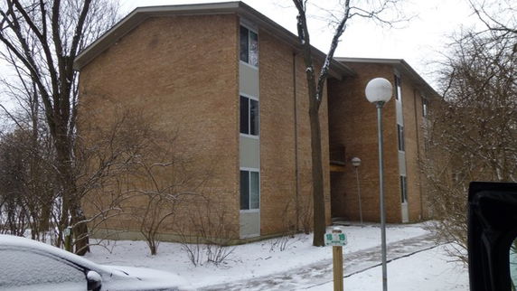 Front view of a multi-story brick building with large windows.