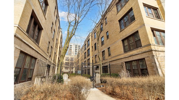 Front view of a multi-story brick building with gated entrance.