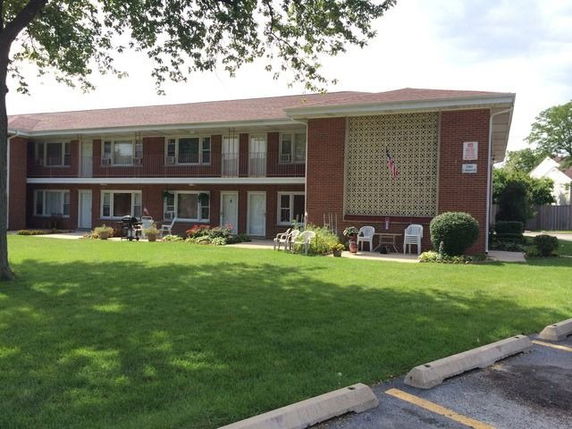 Front view of a two-story brick building with a small patio area and lawn.