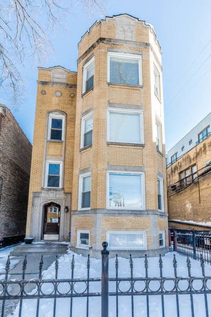 Front view of a multi-story brick building with large windows.