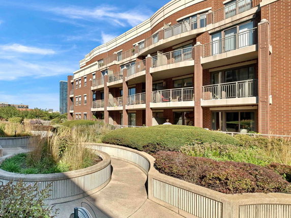 Rooftop garden with plants and seating areas on a brick building.