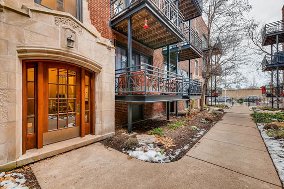Front view of a brick building with balconies and a wooden entrance door.