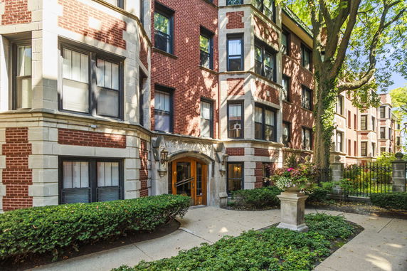 Front view of a multi-story brick apartment building with decorative stone accents.