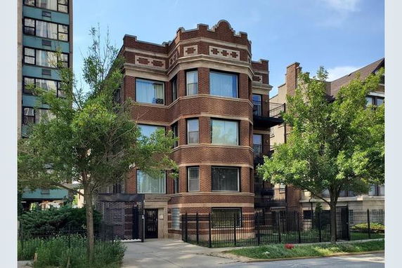 Front view of a three-story brick building with large windows and decorative elements.
