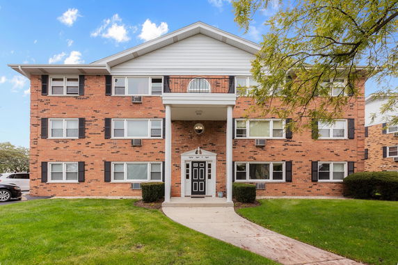 Front view of a three-story brick apartment building with multiple windows and a central entrance.