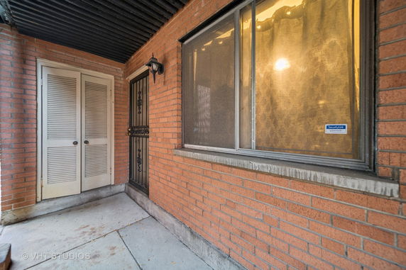 Exterior view of a brick building entrance with a security door and a window.