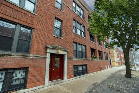 Front view of a multi-story red brick building with large windows and a central entrance.
