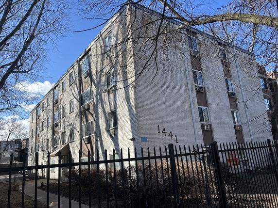Front view of a multi-story building with numbered facade and window air conditioning units.