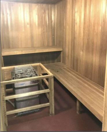 Interior view of a wooden sauna room with benches and a central heating unit.